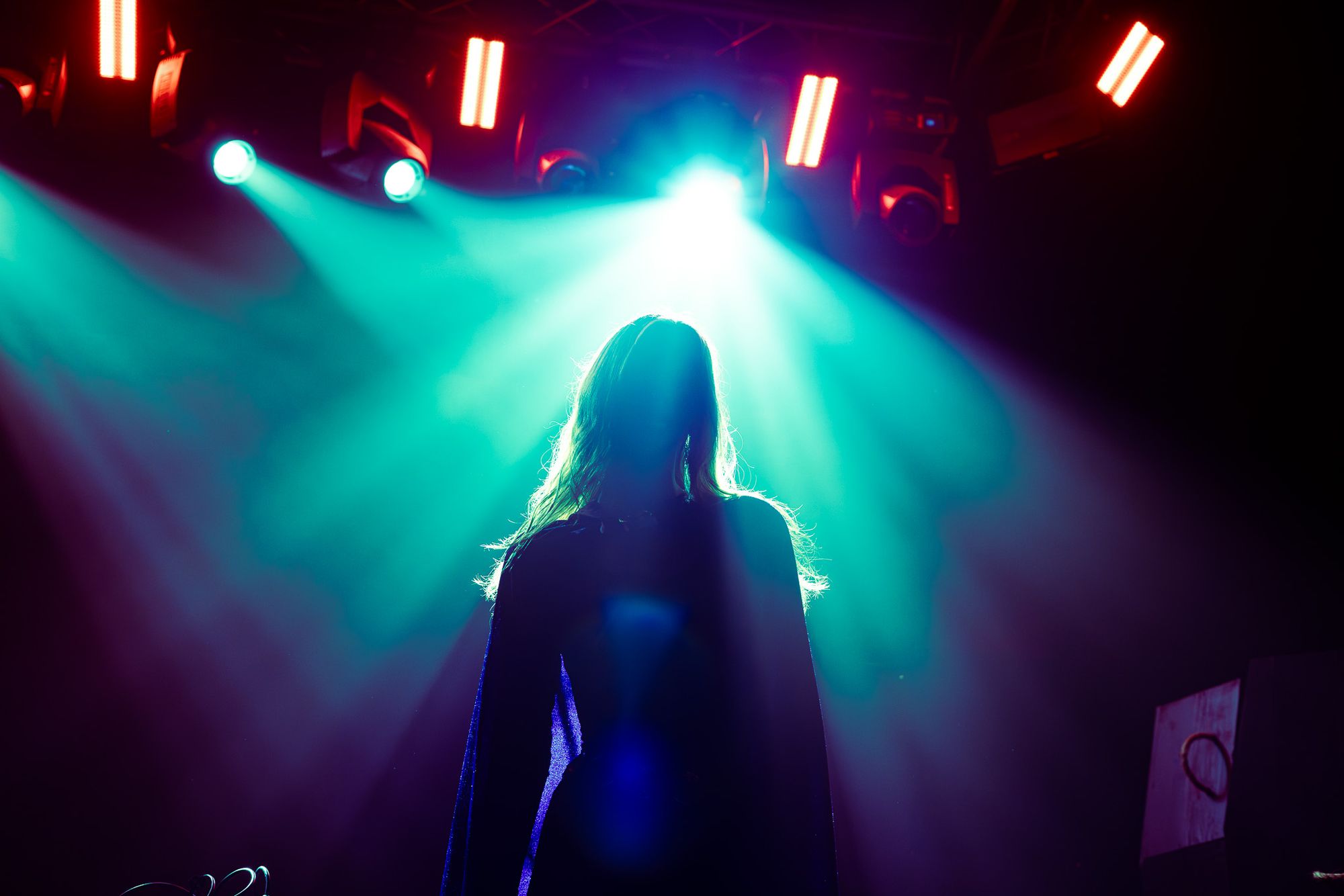 A silhouetted DJ performing beneath pink stage lights